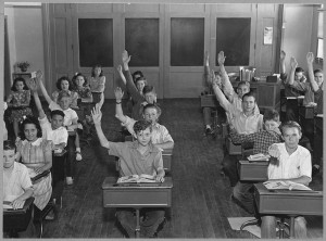 Children in a classroom with hands up facing the camera