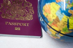 The bottom half of a British passport, next to a globe.